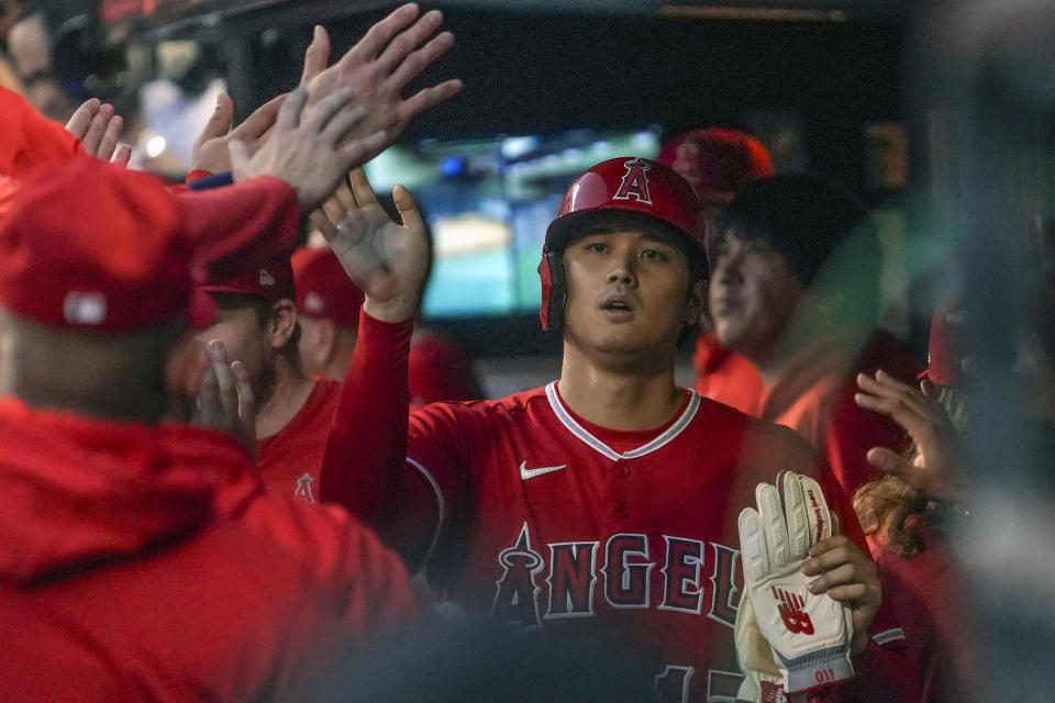 Los Angeles Angels' Shohei Ohtani gets high-fives from teammates in the dugout after scoring run during the first inning of a baseball game against the New York Mets, Saturday, Aug. 26, 2023, in New York. (AP Photo/Bebeto Matthews)