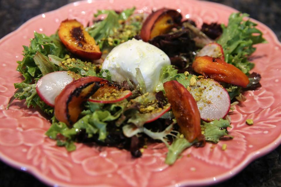 The Burratini Salad with greens, peach, vincotto, pistachio, honey vinaigrette is a popular favorite at Ambrose Restaurant.
