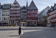 FILE - A couple looks at timberframe houses at the almost empty Roemerberg square, the main tourist spot in Frankfurt, Germany, March 15, 2020. Germany is set to mark 100,000 deaths from COVID-19 this week, passing a somber milestone that several of its neighbors crossed months ago but which some in Western Europe's most populous nation had hoped to avoid. (AP Photo/Michael Probst, File)