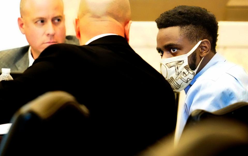 Carl Godfrey, 23, talks with his attorneys, Brian Goldberg, left, and James Bogen, during closing arguments in his murder-for-hire trial, Wednesday, Jan. 31, 2024. The trial is before Hamilton County Common Pleas Judge Jody Luebbers. Godfrey is charged with multiple counts in the deaths of two people on two different days in February 2021. While in the courtroom, Godfrey wore a mask with "Not Guilty" printed in large letters across the front.