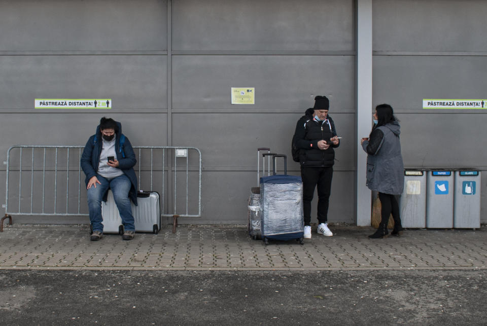 People stand outside the arrivals area of the Sibiu International airport in central Romania, Tuesday, Dec. 28, 2021. As the fast-spreading coronavirus variant omicron rages through Western Europe, officials and experts in low-vaccinated Eastern Europe view it as a forewarning for what much of the region anticipates to be an imminent, post-holiday virus surge.(AP Photo/Stephen McGrath)