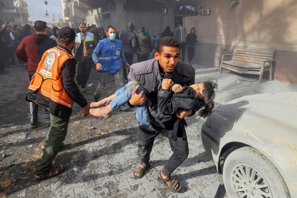 A man carries a child injured in an Israeli strike on Rafah in the southern Gaza Strip on Nov. 20, 2023, amid continuing battles between Israel and the Palestinian militant group Hamas.