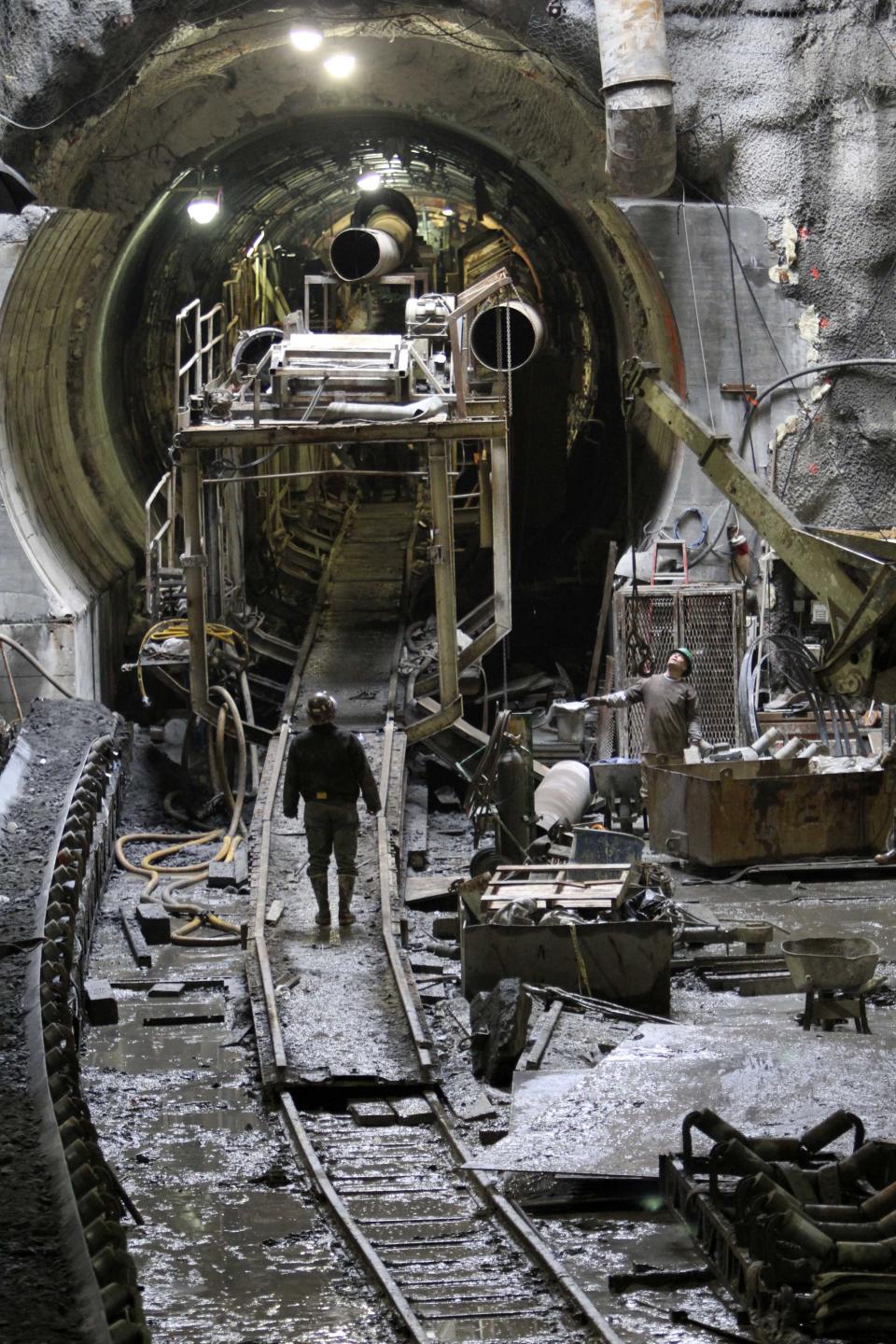 FILE- In this April 7, 2011 file photo, a subway construction worker, known as a "sandhog" enters the tunnel boring machine in the northbound tunnel of the Second Avenue subway construction project in New York. On Monday, July 23, 2012, the last of the 200-ton tunnel boring machines finished its mission and went quiet. The seven machine fleet dug 13 miles of new train tubes deep beneath New York City, boring through bedrock and creating 16 new tunnels in 4 ½ years of digging. (AP Photo/Mary Altaffer, File)