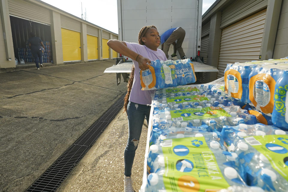 Mississippi Students Water Crisis Advocacy Team member, Mya Grimes, 18, lifts a case of water from one of two pallets delivered to their Jackson, Miss., storage locker that are earmarked for home delivery, on Sept. 8, 2022. A boil-water advisory has been lifted for Mississippi's capital, and the state will stop handing out free bottled water on Saturday. But the crisis isn't over. Water pressure still hasn't been fully restored in Jackson, and some residents say their tap water still comes out looking dirty and smelling like sewage. (AP Photo/Rogelio V. Solis)