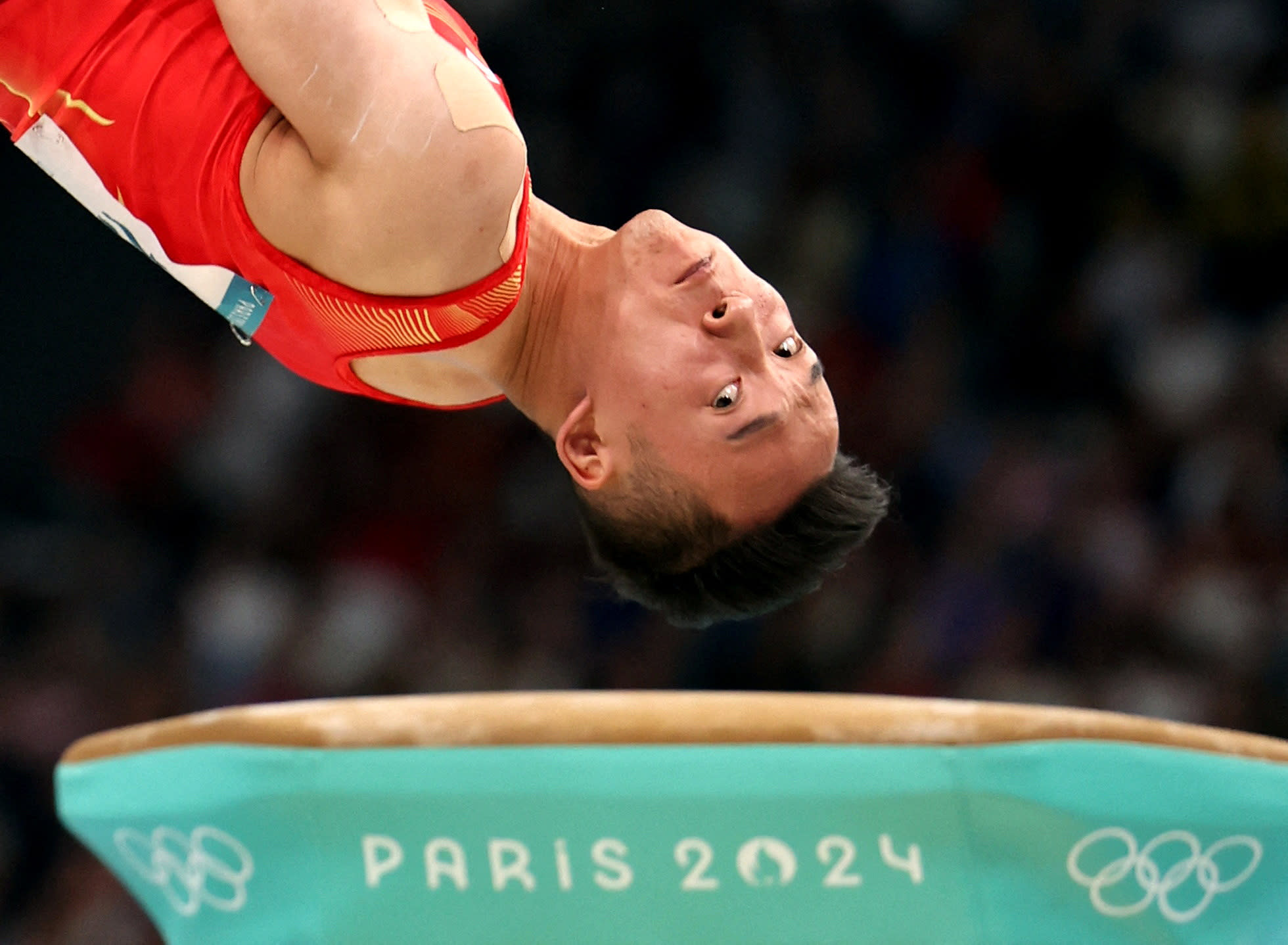 Gymnast Ruoteng Xiao of China in action and upside down on the vault.