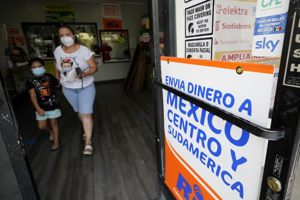 ARCHIVO - Una mujer sale de una tienda que ofrece servicios para enviar remesas a México y Centroamérica, en San Diego, el 11 de septiembre de 2020. (AP Foto/Gregory Bull, Archivo)