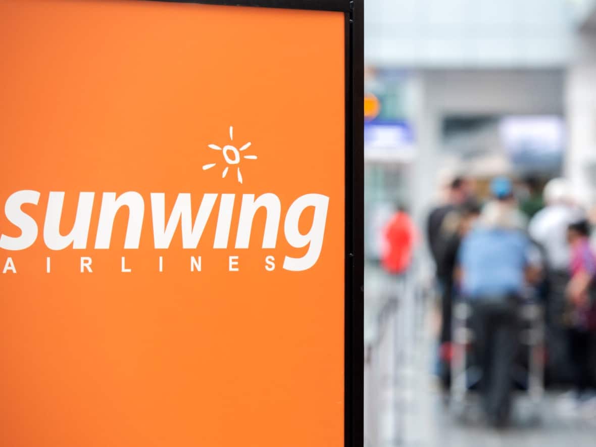 Travellers wait in line at a Sunwing Airlines check-in desk in Montreal. The Hamdan family says they felt left in the cold and in the dark after their Sunwing flight home from Mexico was rescheduled. (Graham Hughes/The Canadian Press - image credit)