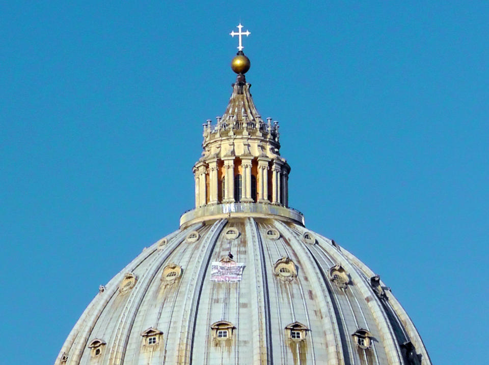 Italian businessman Marcello di Finizio stands by his banner as he protests on St. Peter's 130-meter-high (42-feet-high) dome, at the Vatican, Wednesday, Oct. 3, 2012. Di Finizio eluded Vatican security Tuesday and scaled the dome of St. Peter's Basilica to protest against the Italian government and European Union policies. Officials said Wednesday that the man, who identified himself as the owner of a beach resort, refused appeals from government ministers offering to meet with him if he would come down. (AP Photo/Paolo Santalucia)