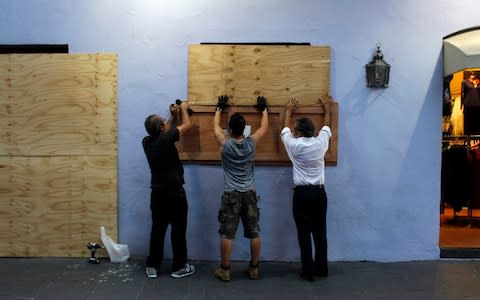 People board up windows of a business in preparation for the anticipated arrival of Hurricane Maria in San Juan, Puerto Rico - Credit: AFP