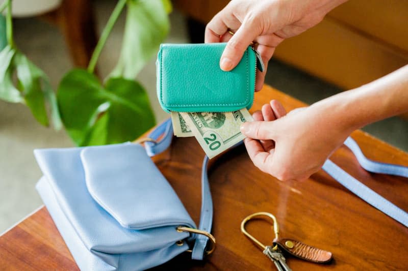 <span>Taking a $20 bill out of a green wallet, with blue purse, keys on table Credit: <a href="https://sarahecrowley.com/" rel="nofollow noopener" target="_blank" data-ylk="slk:Sarah Crowley;elm:context_link;itc:0;sec:content-canvas" class="link ">Sarah Crowley</a></span> <span class="copyright">Credit: <a href="https://sarahecrowley.com/" rel="nofollow noopener" target="_blank" data-ylk="slk:Sarah Crowley;elm:context_link;itc:0;sec:content-canvas" class="link ">Sarah Crowley</a></span>
