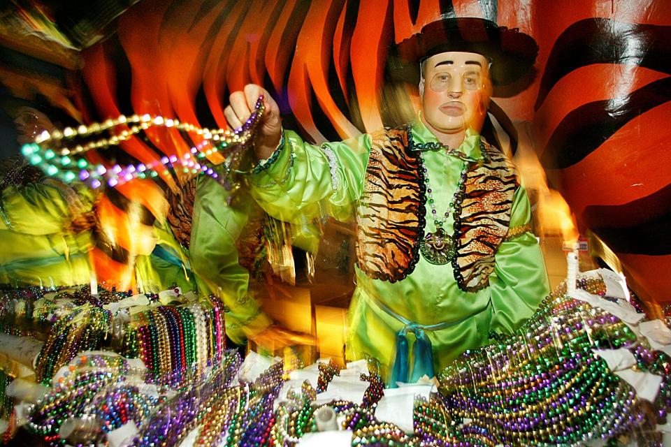 A reveler from the Mystic Stripers Society tosses beads to the crowd along South Claiborne Street, in this Feb. 23, 2006, file photo, in downtown Mobile, Ala. (AP Photo/Mobile Register, John David Mercer/FILE)