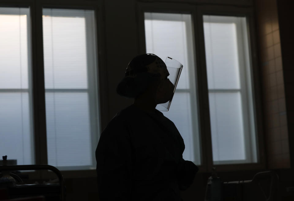 A healthcare worker is silhouetted against the window during a shift in an intensive care unit (ICU) at the General University Hospital where patients infected with the COVID-19 are treated in Prague, Czech Republic, Tuesday, April 7, 2020. The new coronavirus causes mild or moderate symptoms for most people, but for some, especially older adults and people with existing health problems, it can cause more severe illness or death. (AP Photo/Petr David Josek)