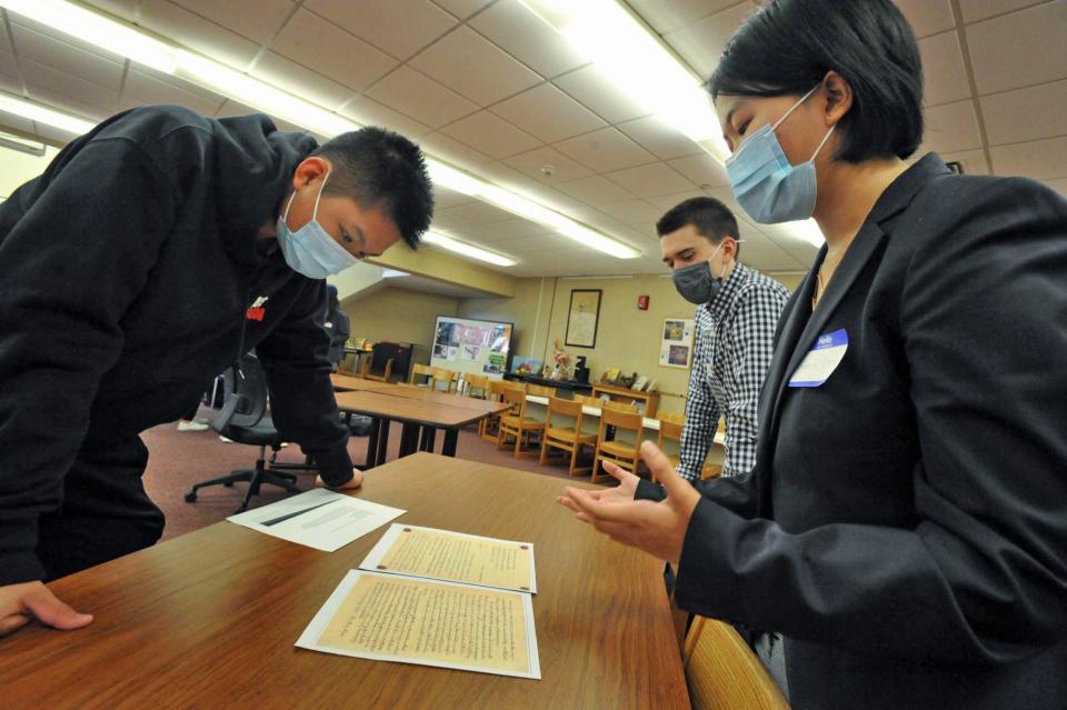 North Quincy High School student Andy Zheng, left, looks at letters written by President John Quincy Adams as North Quincy high sophomores and docents John Thomas, center, and Candace Chan, right, provide information Friday, April 29, 2022.