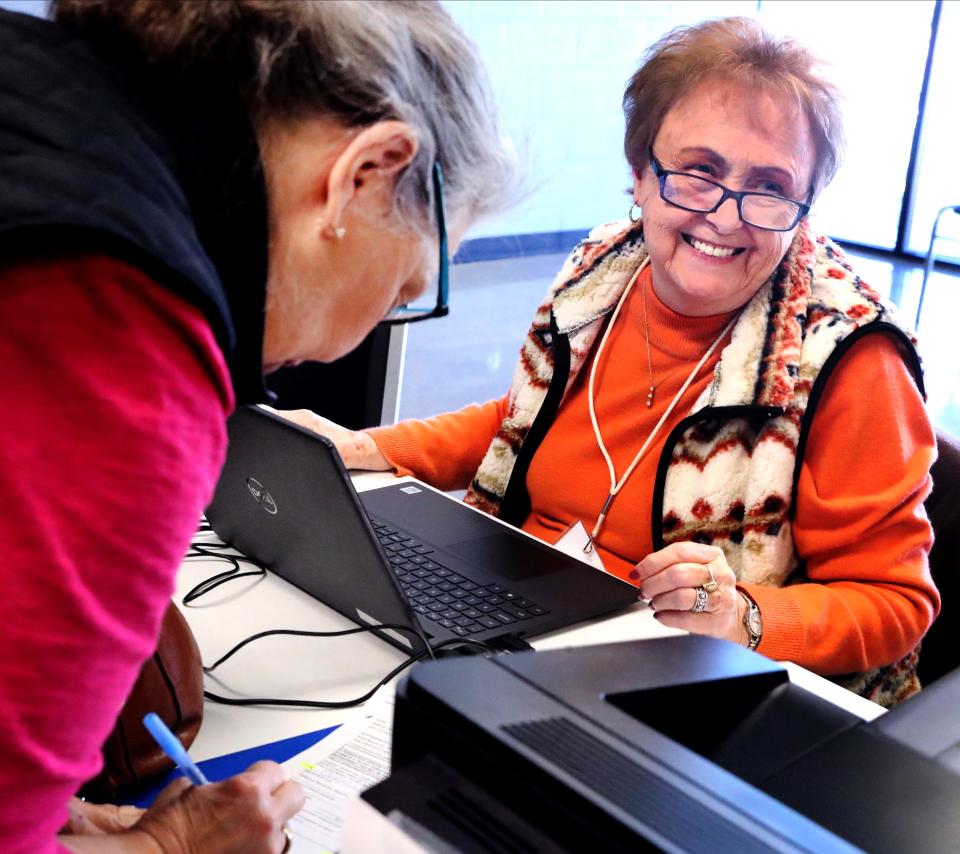 Linda Wilson, right is all smiles as she gets Debbi Martin's paperwork ready to vote at SportsCom during the first day of early voting on Wednesday, Oct. 19, 2022.