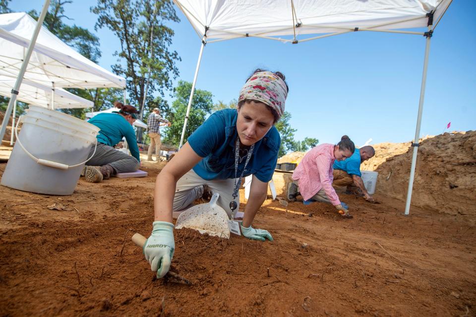 Archeologists Stacia Yoakam, center, of Marysville, Ohio, Gabby Lofland of Sussex County, Del., left, and from right, Dustin Clarke of Ft. Walton Beach, Fla., and Moriah Baleigh of Lexington, Ky., use trowels to carefully scrape away the soil of gravesites at Asylum Hill at University of Mississippi Medical Center in Jackson, Miss., Friday, Aug. 18, 2023. The ongoing excavation of the remains of patients who died at the Mississippi State Lunatic Asylum focuses on study and respectfully memorializing the bodies of patients who were never claimed.