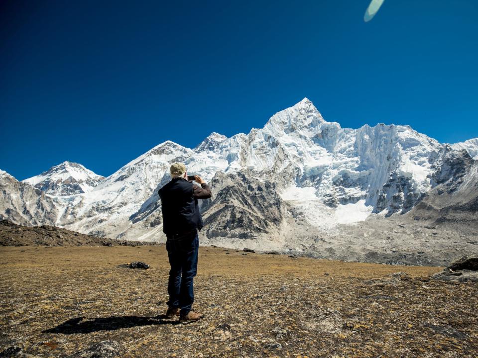 A person taking a picture of a snow mountain range.