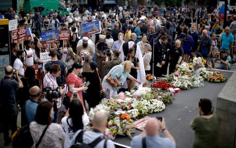 People look at flowers laid after a minute's silence on London Bridge to mark the one year anniversary of the attack - Credit:  Matt Dunham/AP