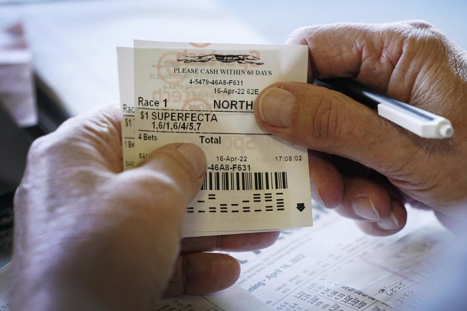 A man holds his betting slips while waiting for a race at the Iowa Greyhound Park, Saturday, April 16, 2022, in Dubuque, Iowa. After the end of a truncated season in Dubuque in May, the track here will close. By the end of the year, there will only be two tracks left in the country. (AP Photo/Charlie Neibergall)