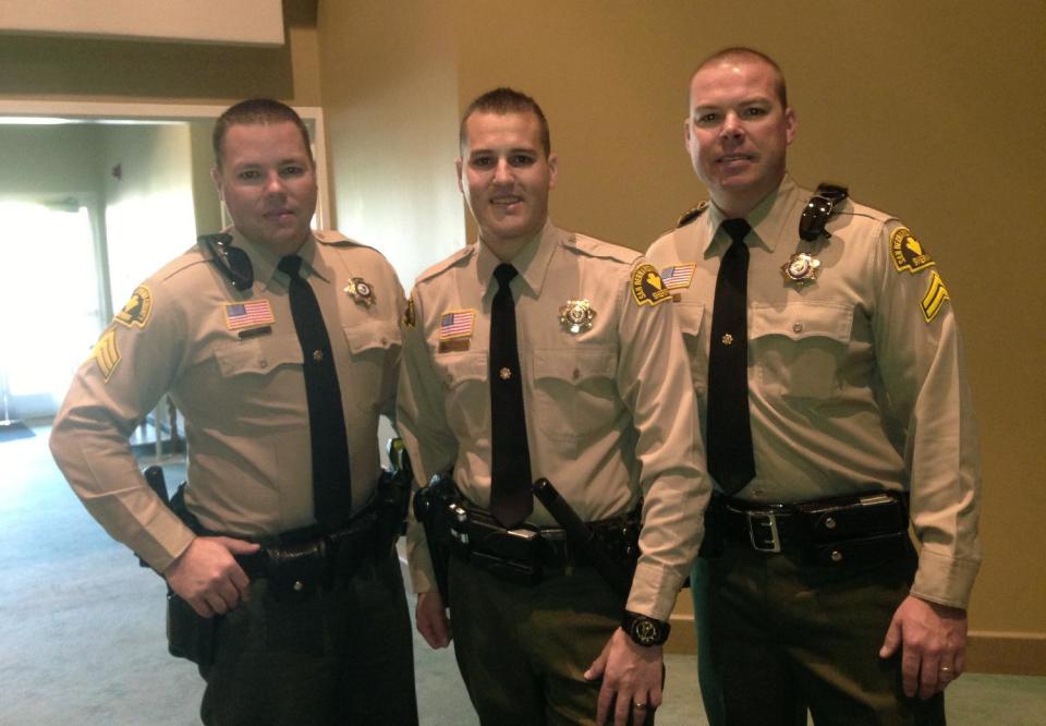 In this May 14, 2013 photo provided courtesy of Lila Collins shows San Bernandino County Sheriff's Department deputies and brothers, Sgt. Ryan Collins, 39, left, Det. Alex Collins, 27, center and and SWAT Det. Matt Collins, 37. (AP Photo/Lila Collins)