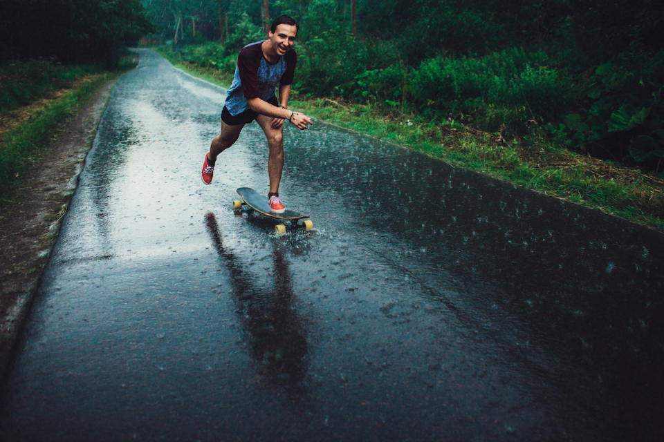 Young man longboarding in forest