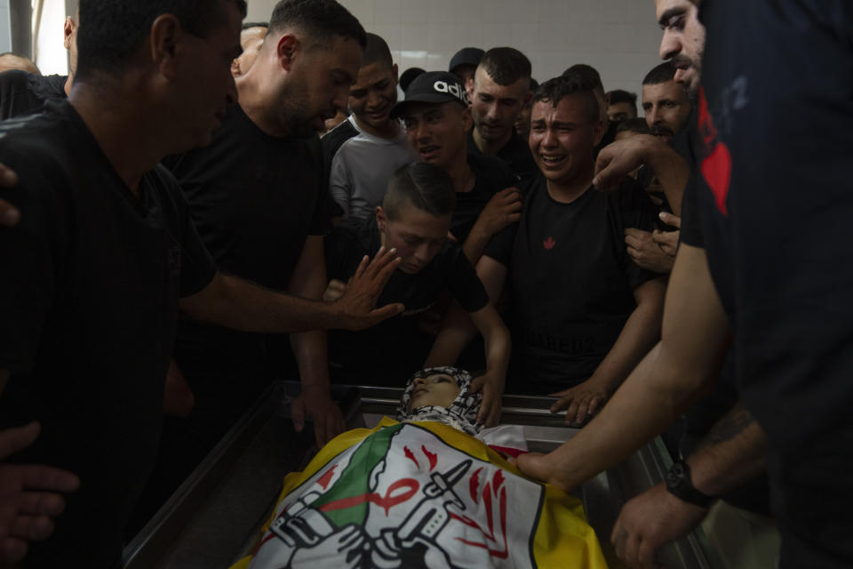 Mourners cry while they take the last look at the body of Fares Abu Samra, 14, during his funeral in the West Bank city of Qalqilya, Thursday, July 27, 2023. The Palestinian Health Ministry said Thursday that Abu Samra was killed by Israeli fire in Qalqilya. The Israeli military said Palestinians threw rocks and firebombs at troops, who responded by firing into the air. It said the incident was being reviewed. (AP Photo/Nasser Nasser)