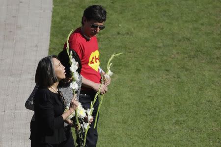 Florinda Meza (L), widow of the late screenwriter Roberto Gomez Bolanos, is accompanied by his son Roberto Gomez (top) before placing flowers on the pitch of the Azteca stadium before the start of a mass held in his honour in Mexico City November 30, 2014. REUTERS/Tomas Bravo