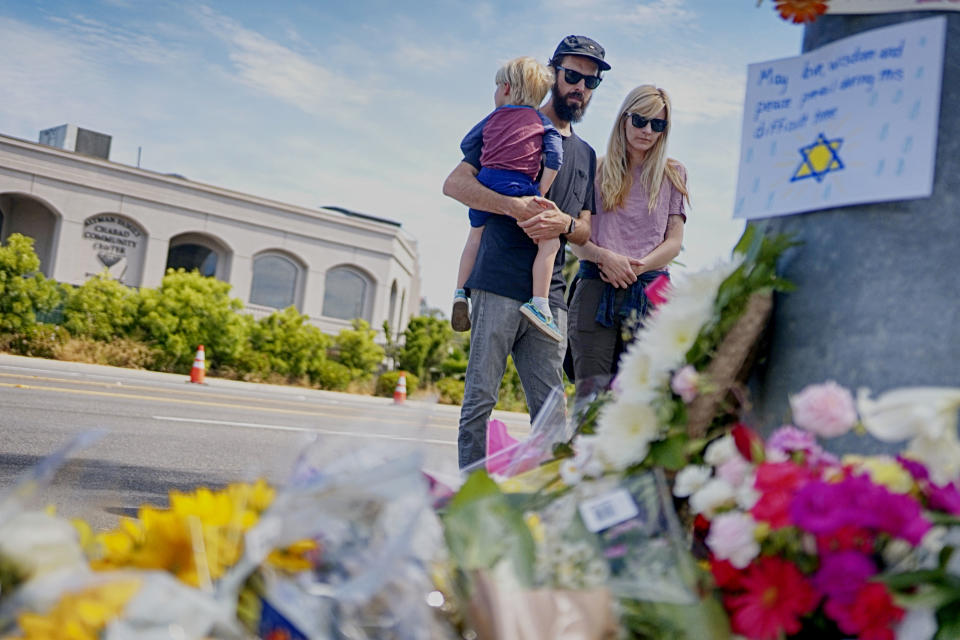 Mourners look over a make-shift memorial across the street from the Chabad of Poway Synagogue on Sunday, April 28, 2019 in Poway, California, one day after a teenage gunman opened fire, killing one person and injuring three others including the rabbi as worshippers marked the final day of Passover, authorities said. (Sandy Huffaker/AFP via Getty Images)