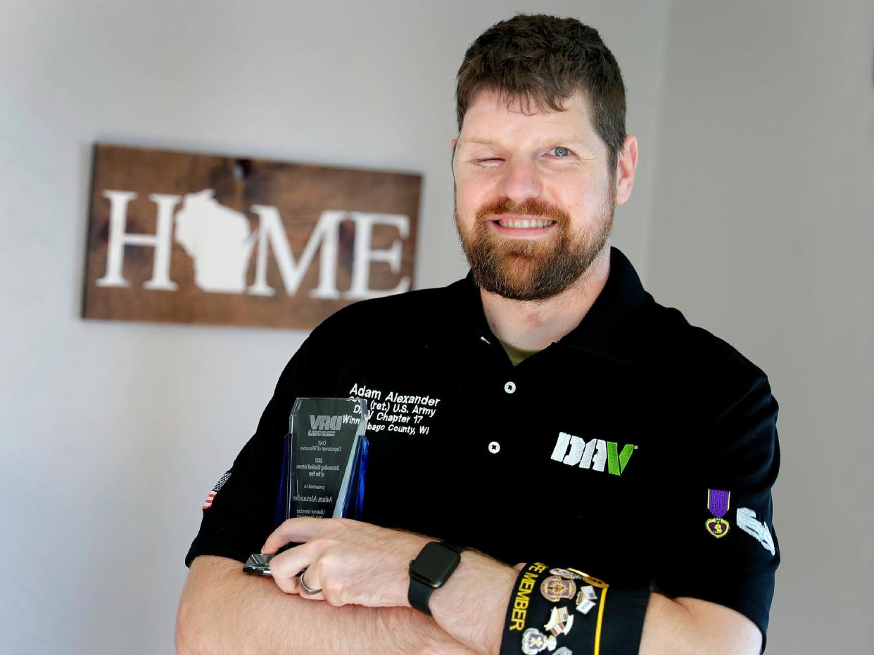 United States Army veteran Adam Alexander poses with his Disabled American Veterans award Friday at his home in Oshkosh.