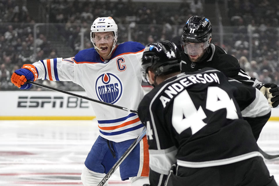 Edmonton Oilers center Connor McDavid, left, battles with Los Angeles Kings center Anze Kopitar, right, and defenseman Mikey Anderson during the third period in Game 4 of an NHL hockey Stanley Cup first-round playoff series Sunday, April 28, 2024, in Los Angeles. (AP Photo/Mark J. Terrill)