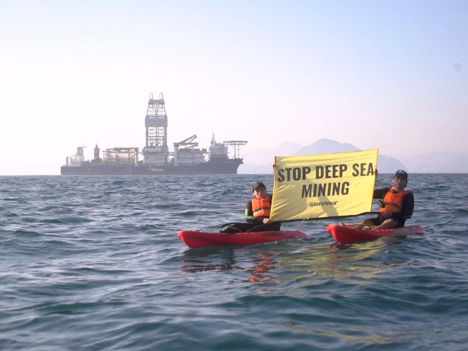 Two demonstrators in Kayaks hold a sign that reads "stop deep sea mining."