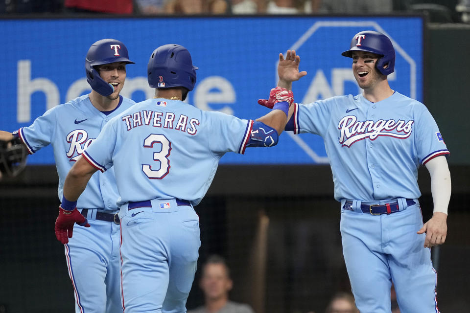 Texas Rangers' Leody Taveras (3), Evan Carter, left rear, and Mitch Garver, right, celebrate at the plate after Taveras hit a two-run home run that also scored Garver in the fourth inning of a baseball game against the Seattle Mariners, Sunday, Sept. 24, 2023, in Arlington, Texas. (AP Photo/Tony Gutierrez)