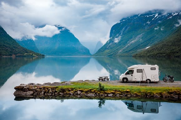 RV parked on a lake promontory amid mountains.
