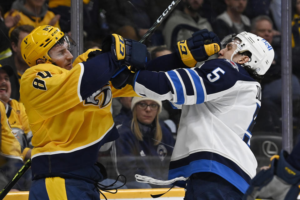 Winnipeg Jets defenseman Brenden Dillon (5) scuffles with Nashville Predators left wing Tanner Jeannot (84) during the second period of an NHL hockey game Tuesday, Jan. 24, 2023, in Nashville, Tenn. (AP Photo/Mark Zaleski)