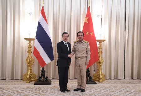 Chinese Foreign Minister Wang Yi (L) shakes hands with Thai Prime Minister Prayuth Chan-O-Cha (R) at Government House in Bangkok, Thailand July 24, 2017. REUTERS/Lillian Suwanrumpha/Pool