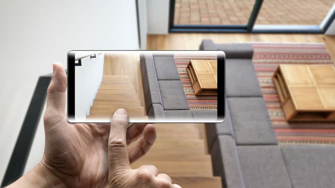 Two hands holding a mobile Smartphone taking picture on Hardwood stairs and ramp in modern renovated living room.