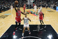 Chicago Bulls guard Ayo Dosunmu (12) scores past San Antonio Spurs forward Keldon Johnson (3) during the second half of an NBA basketball game, Friday, Jan. 28, 2022, in San Antonio. (AP Photo/Eric Gay)