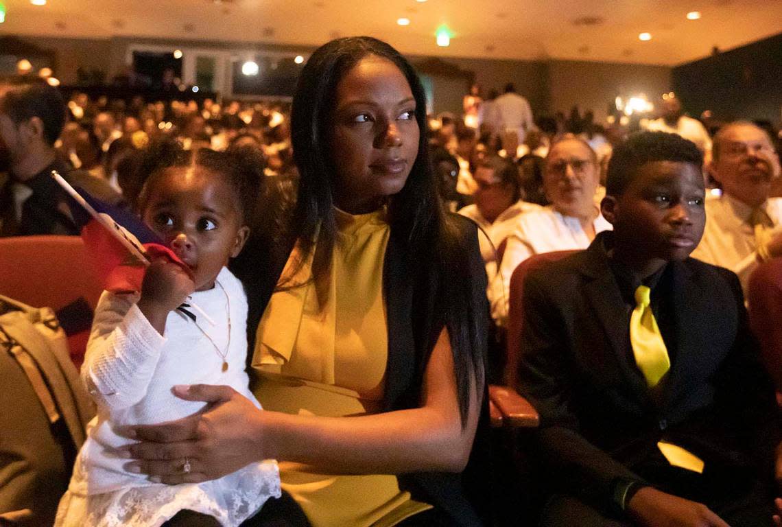 Mikaben’s wife, Vanessa Benjamin, holds their daughter 1-year-old Leïa Benjamin, next to his son Gabriel at a memorial service for Haitian singer Mikaben in Miramar on Sunday. The popular artist died in Paris while performing.