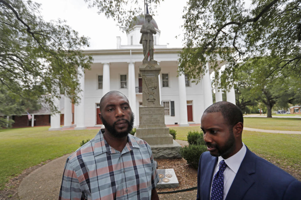 FILE - In a Wednesday, Aug. 1, 2018 file photo, Ronnie Anderson, left, an African-American man charged with possession of a firearm by a convicted felon, stands with his lawyer Niles Haymer in front of a confederate statue on the lawn of the East Feliciana Parish Courthouse, where he is facing the charge, in Clinton, La. A legal argument has been revived in Louisiana over whether a Anderson can get a fair trial in a courthouse where a Confederate monument is displayed. Haymer released copies Tuesday, Sept. 18, 2018, of his new motion to have Anderson's case moved out of state court in the city of Clinton. (AP Photo/Gerald Herbert, File)