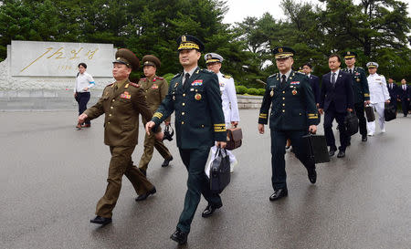 North and South Korean delegation walk as they cross the concrete border at the northern side of the truce village of Panmunjom, in North Korea, June 14, 2018. Yonhap via REUTERS