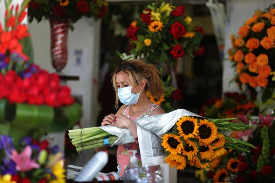 A flower seller waits for customers on the first day of the reopening of Los Angeles flower market.