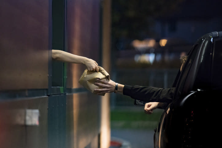 a person handing over a bag at a drive-thru