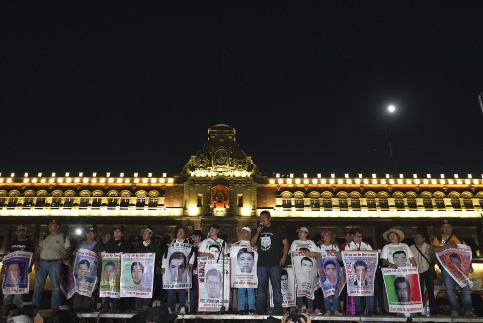 Relatives of 43 missing Ayotzinapa university students hold signs with images and the names of their missing loved ones, on the 9th anniversary of their disappearance, in front the National Palace in Mexico City, Tuesday, Sept. 26, 2023. (AP Photo/Marco Ugarte)