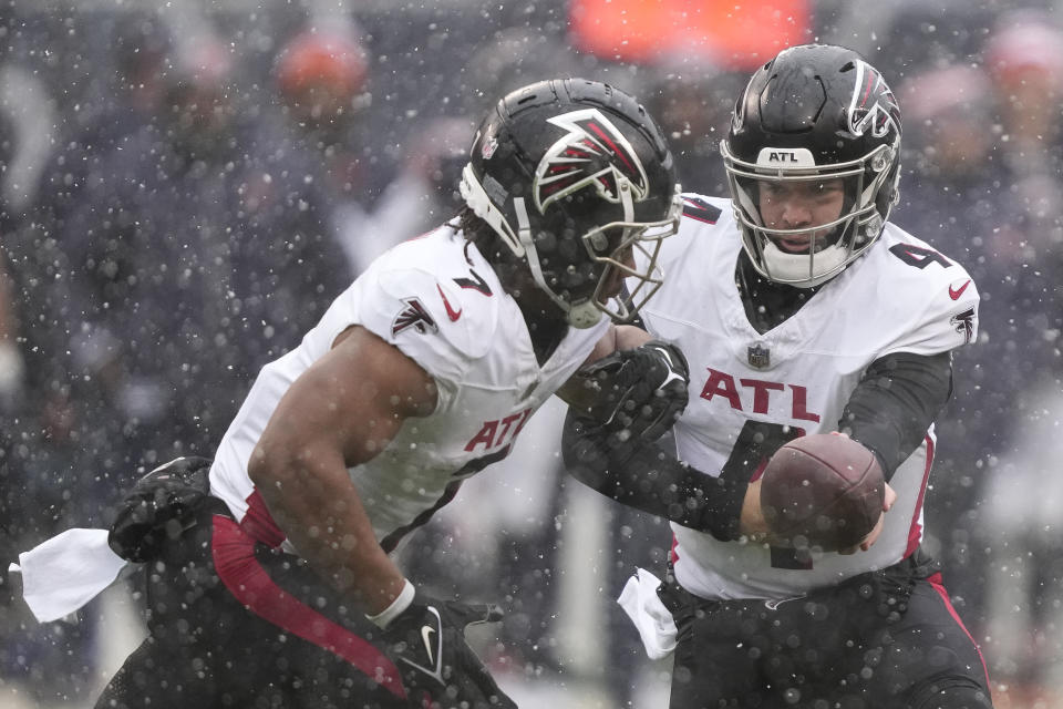 Atlanta Falcons quarterback Taylor Heinicke (4) hands the ball off to Atlanta Falcons running back Bijan Robinson (7) in the first half of an NFL football game against the Chicago Bears in Chicago, Sunday, Dec. 31, 2023. (AP Photo/Charles Rex Arbogast)