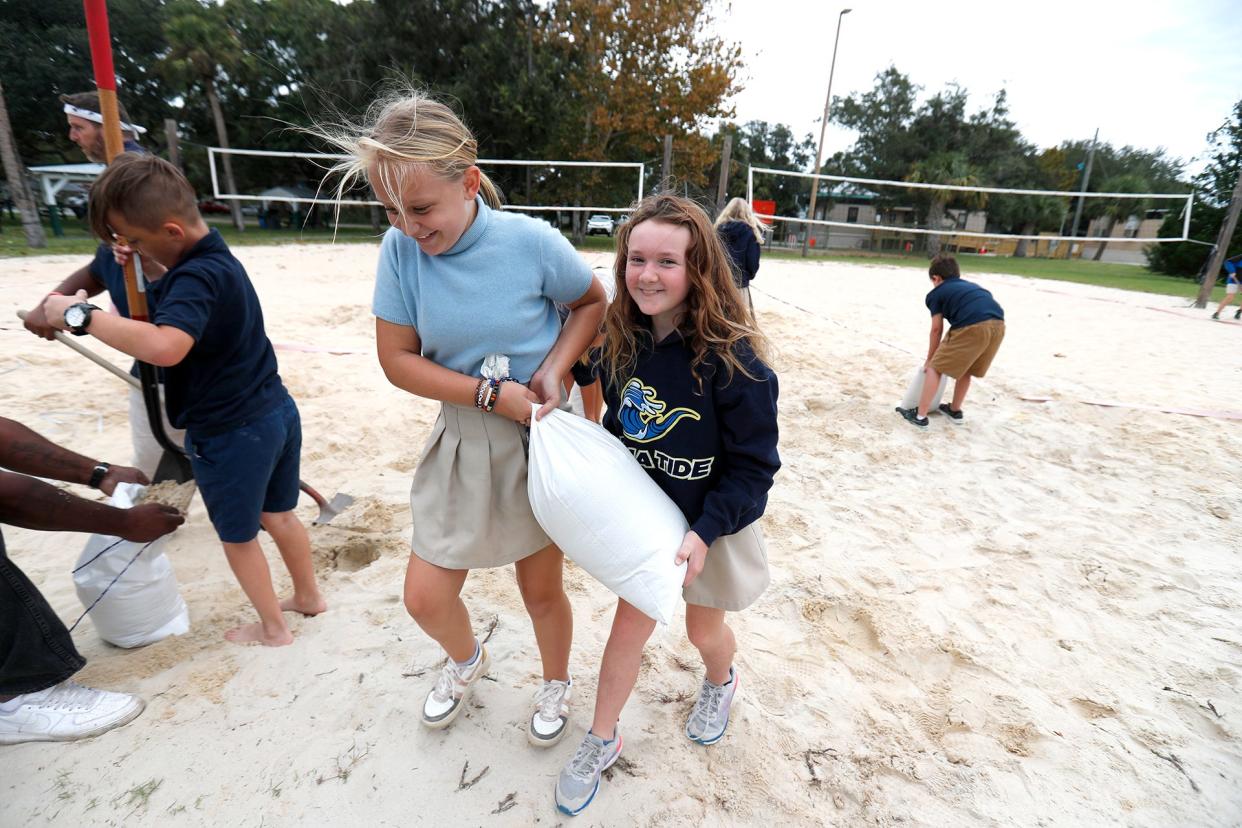 Students from Tybee Island Maritime Academy carry a sand bag for a resident on Wednesday at Memorial Park on Tybee Island. 