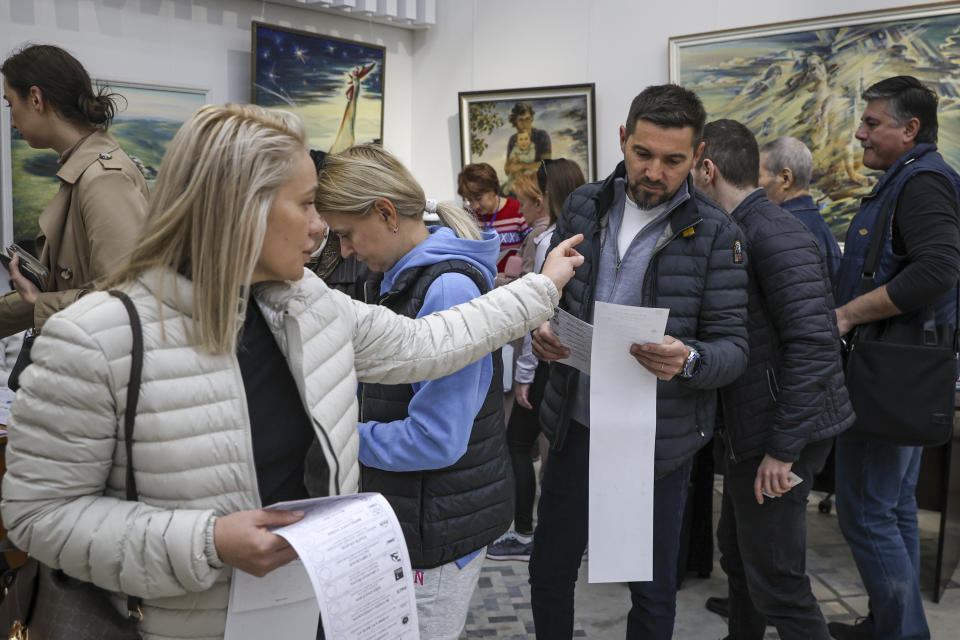 A woman gestures towards a man looking at the candidates lists on the ballot during local elections in Chisinau, Moldova, Sunday, Nov. 5, 2023. Moldovans will cast ballots in nationwide local elections on Sunday amid claims by Moldovan authorities that Russia has been conducting a "hybrid warfare" to undermine the vote in the European Union candidate country. (AP Photo/Aurel Obreja)