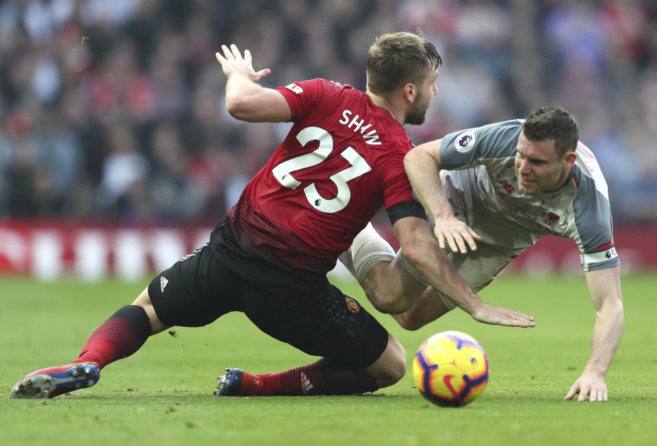 Manchester United's Luke Shaw, left, and Liverpool's James Milner challenge for the ball during the English Premier League soccer match between Manchester United and Liverpool at Old Trafford stadium in Manchester, England, Sunday, Feb. 24, 2019. (AP Photo/Jon Super)