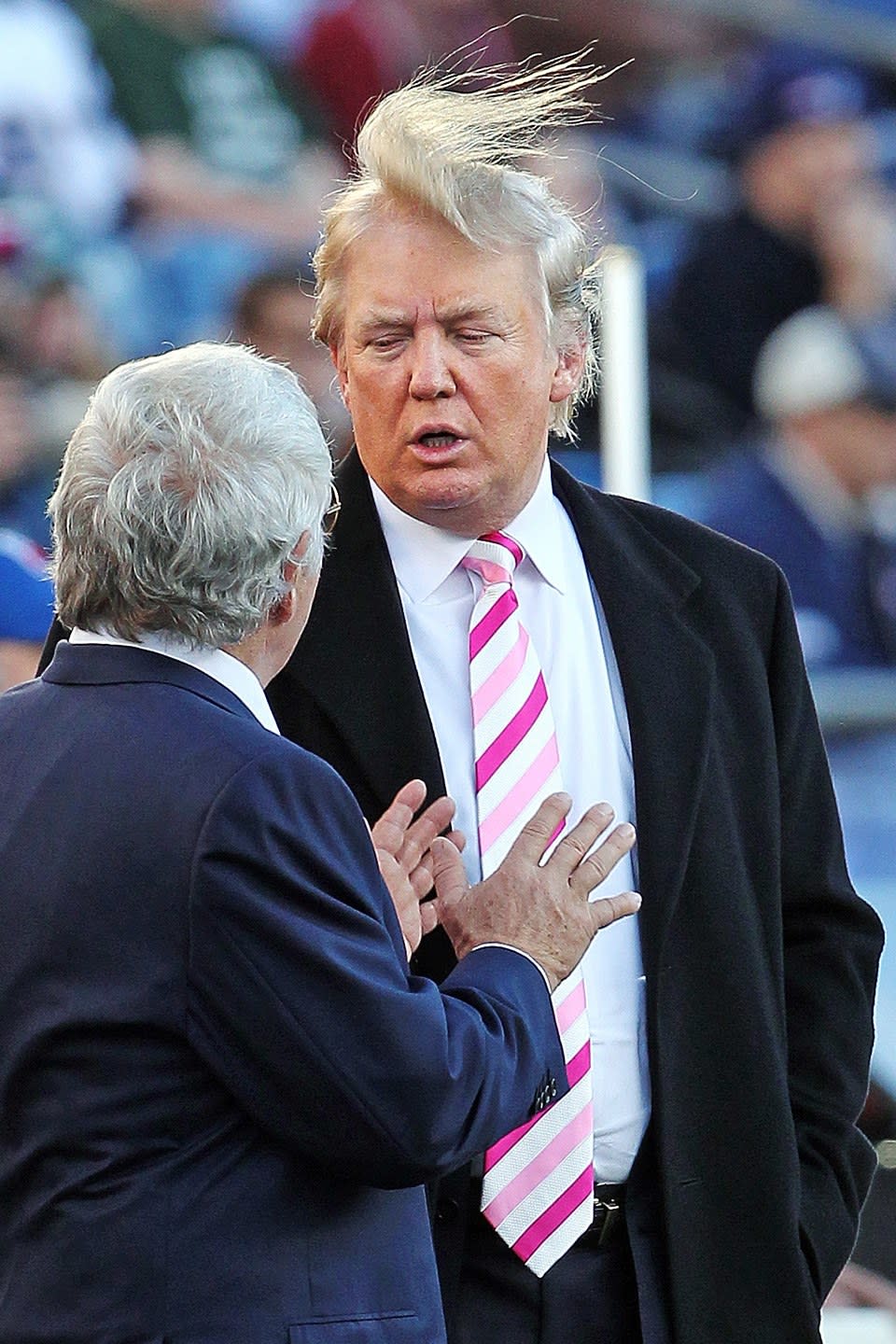 Losing to wind while he talks to Patriots owner Robert Kraft before a game.