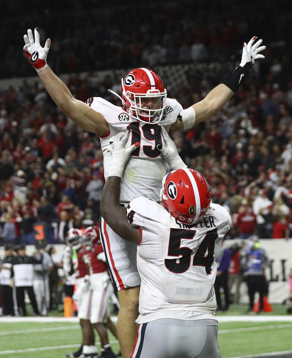 Georgia tight end Brock Bowers gets a hoist from Justin Shaffer after scoring on a 15 yard pass to take a 26-18 lead over Alabama during the 4th quarter in the College Football Playoff Championship game on Monday, Jan. 10, 2022, in Indianapolis. (Curtis Compton/Atlanta Journal-Constitution via AP)