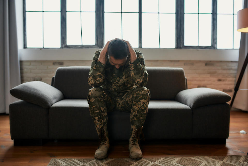 Military man holding his head in frustration as he suffers from psychological trauma