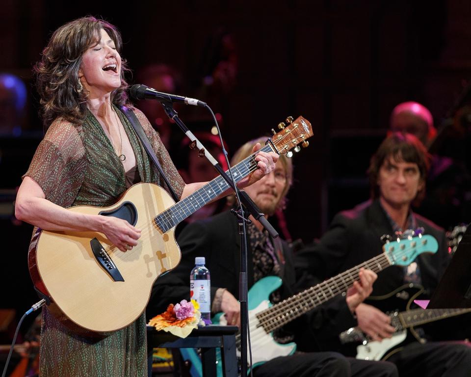 A woman sings and plays a guitar.